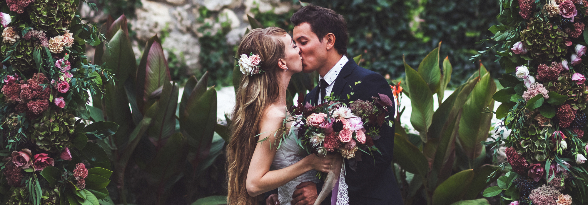 bride and groom kissing amidst beautiful florals 